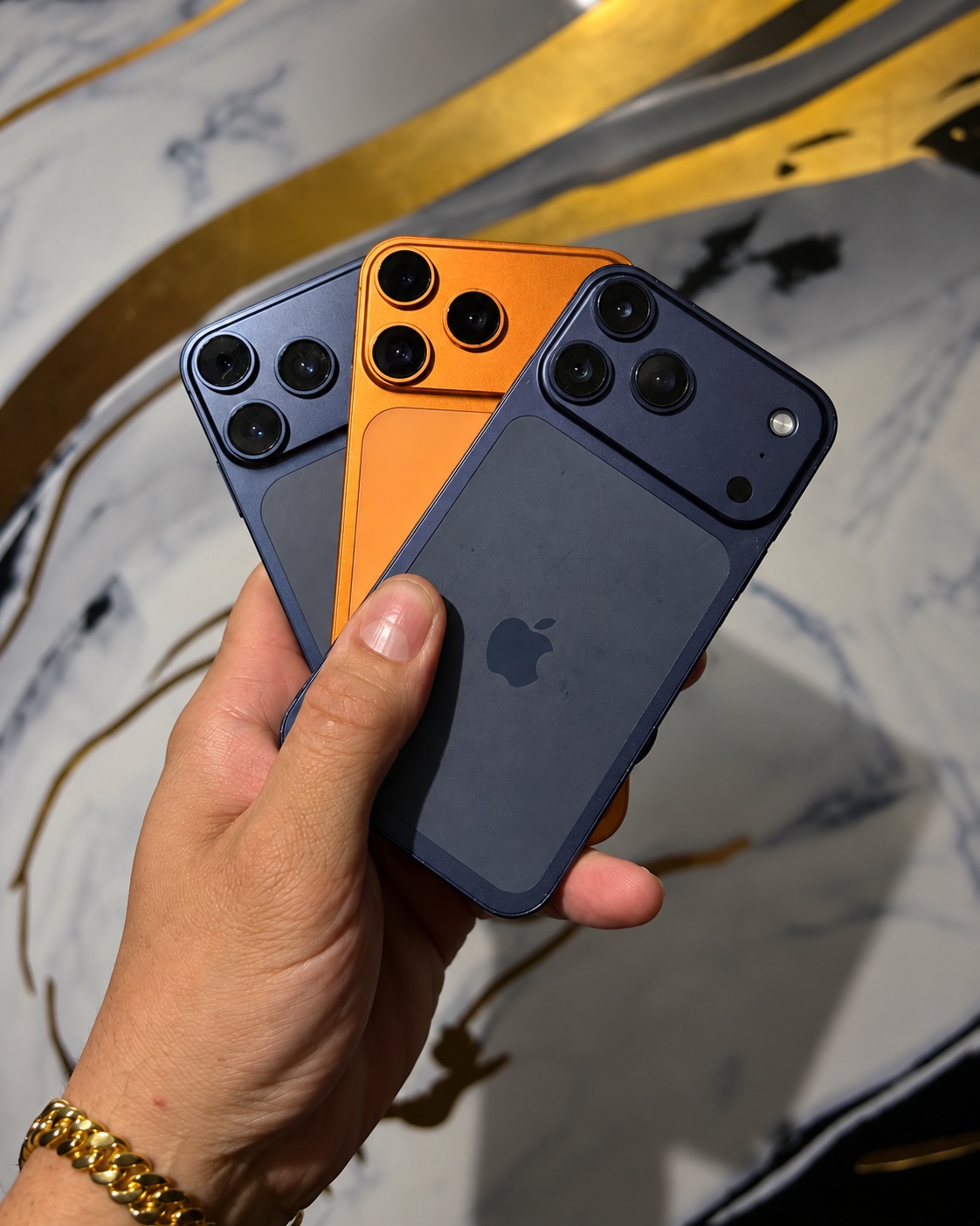 Três aparelhos azul e laranja com visual adaptado, em conjunto na mão